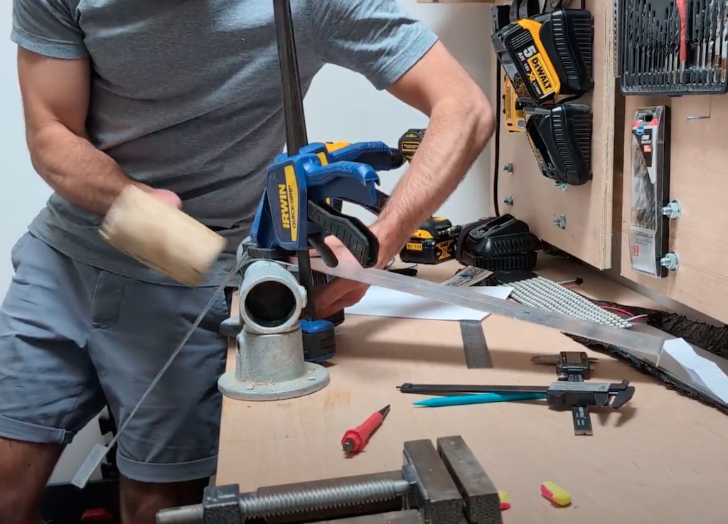 Bending aluminium strip using a piece of scaffold tube, clamps and a big hammer